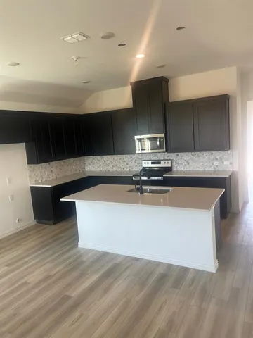 a kitchen with kitchen island stainless steel appliances a sink and a stove