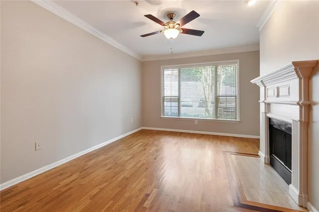 an empty room with wooden floor fireplace and windows
