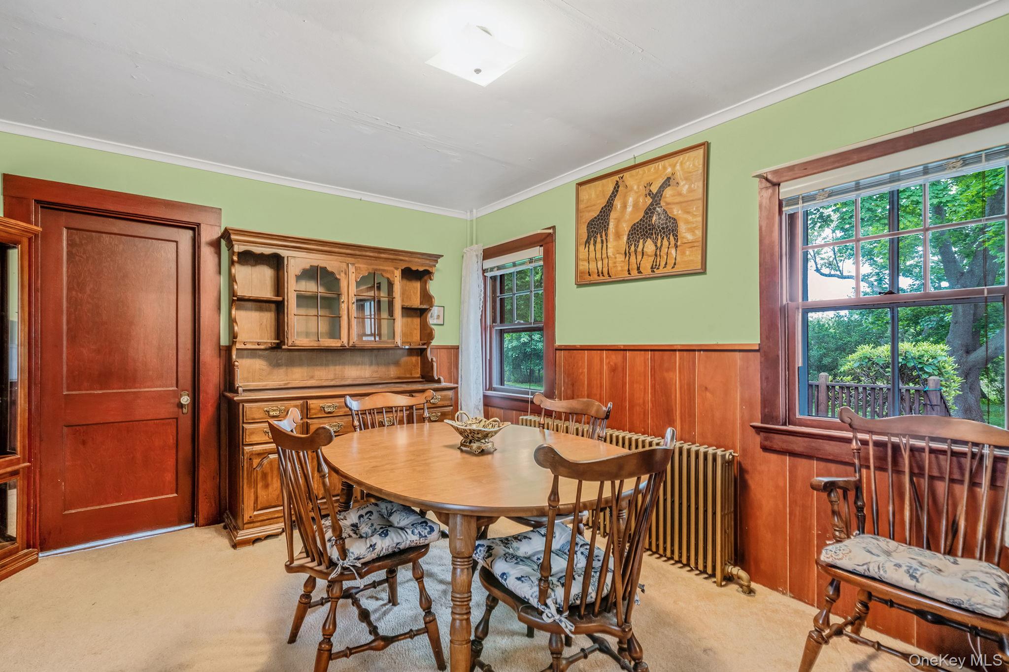 1055 Oregon Road Mattituck, NY 11952 - Photo 12 of 33 Dining room featuring wood paneling, two windows with exterior views, and a warm wood-finish door to 2nd floor.
