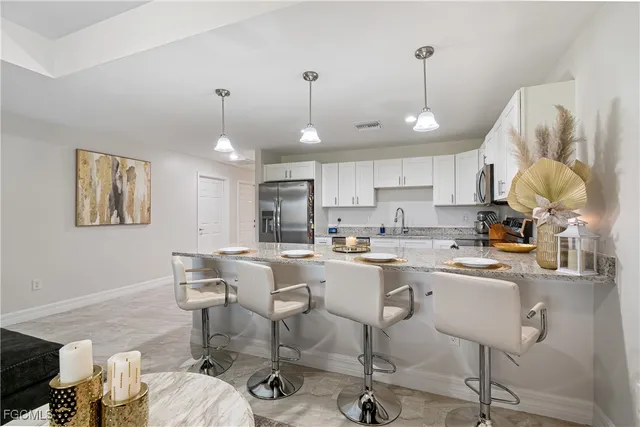 a room with stainless steel appliances kitchen island granite countertop furniture and a dining table