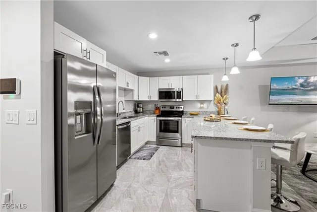 a kitchen with stainless steel appliances granite countertop a refrigerator a sink dishwasher a stove and a refrigerator with wooden floor