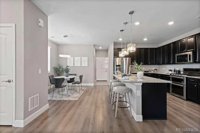 a kitchen with stainless steel appliances kitchen island granite countertop a table chairs in it and wooden floors