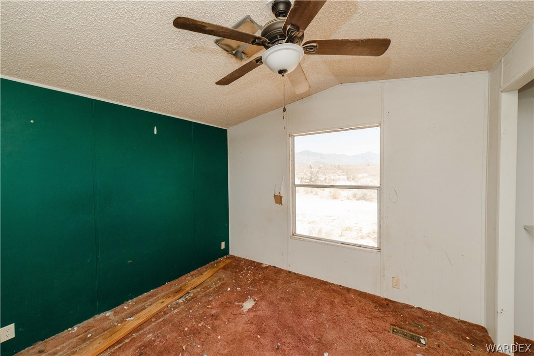 16435 South Wyatt Earp Road Yucca, AZ 86438 - Photo 9 of 57 Interior room with a ceiling fan light fixture, a window providing natural light, and a green accent wall