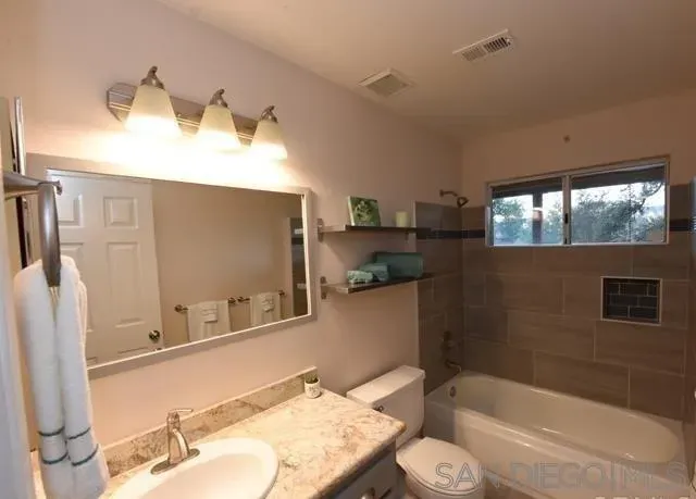 a bathroom with a granite countertop sink toilet and shower