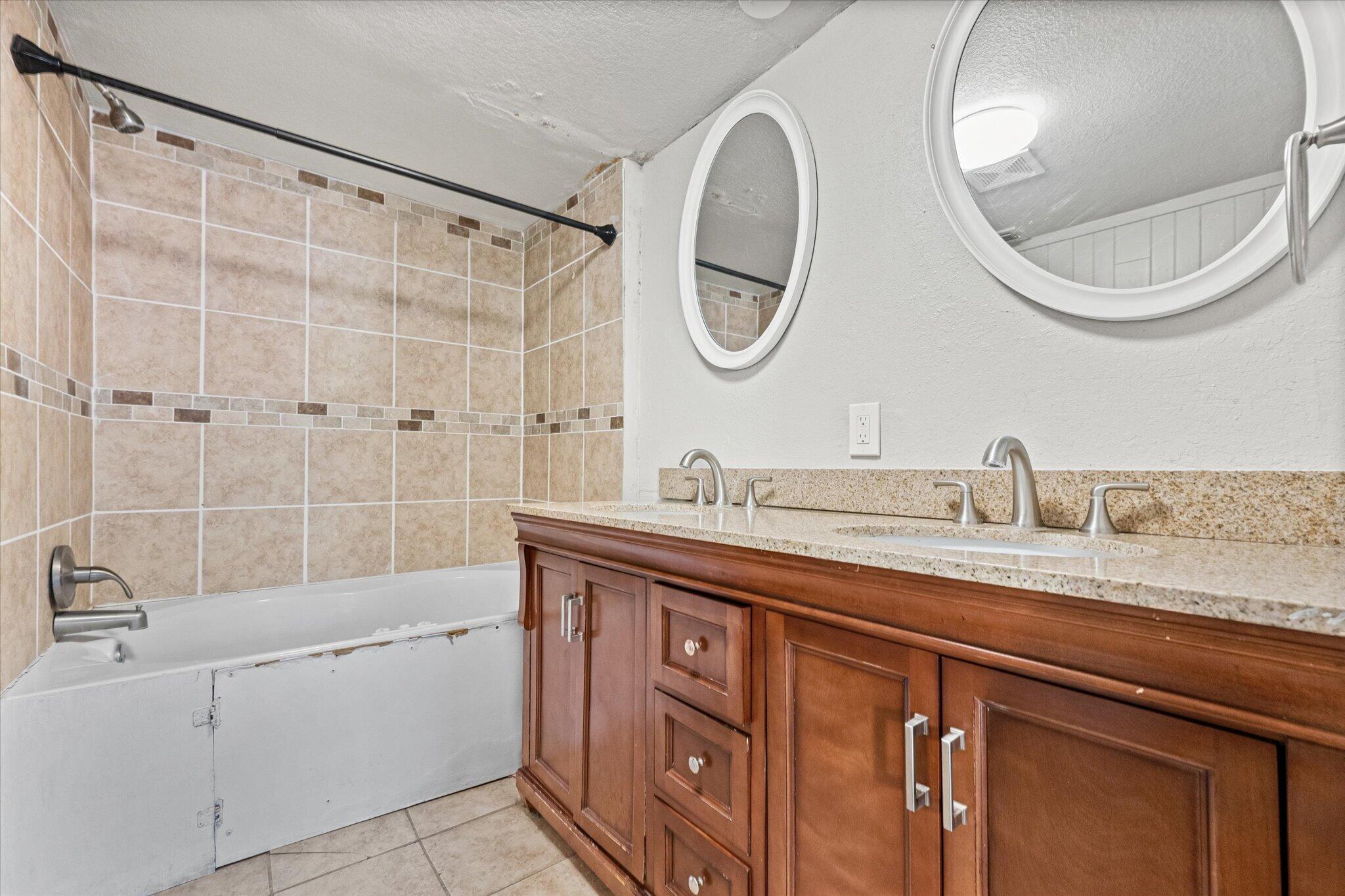 69 Pony Express Trail Lubbock, TX 79404 - Photo 28 of 39 a bathroom with a granite countertop sink a mirror a vanity and a bathtub