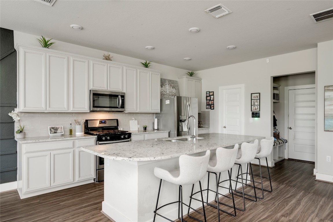 7502 Chesapeake Rail Lane, Unit 154 Austin, TX 78744 - Photo 6 of 40 a kitchen with stainless steel appliances a microwave a stove a sink dishwasher a stove and white cabinets with wooden floor