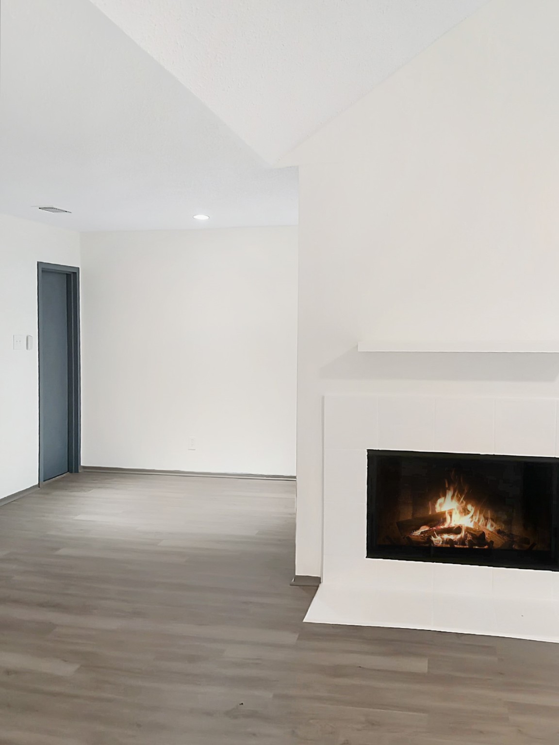 a view of an empty room with wooden floor and a fireplace