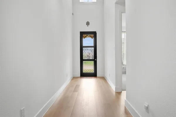 a view of a hallway with wooden floor and a window