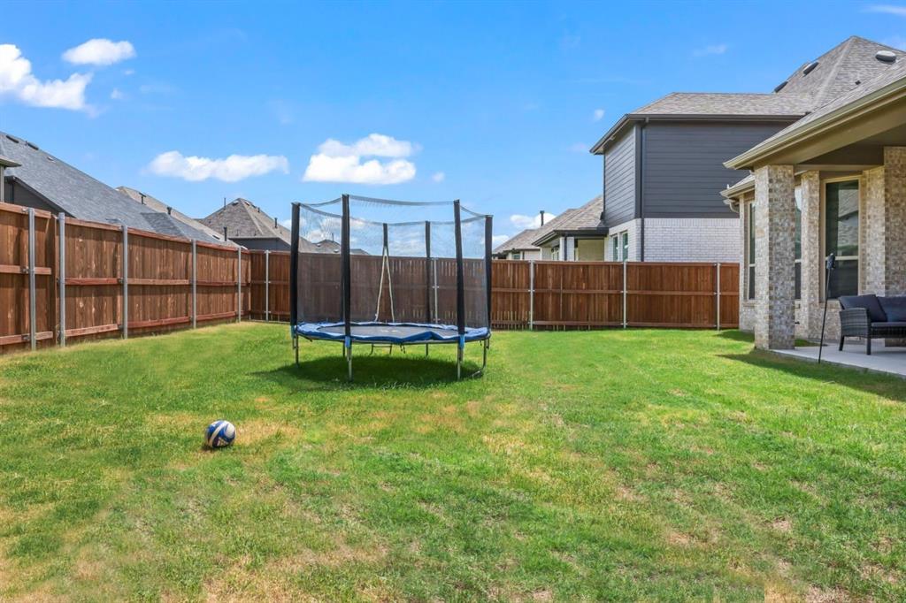 1255 Sumner Street Aubrey, TX 76227 - Photo 40 of 40 a view of a backyard with a garden and fire pit