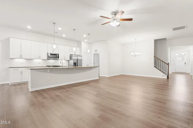 an empty room with wooden floor fan and windows
