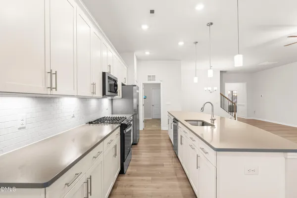 a view of a kitchen with kitchen island a large counter top space a sink stainless steel appliances and cabinets