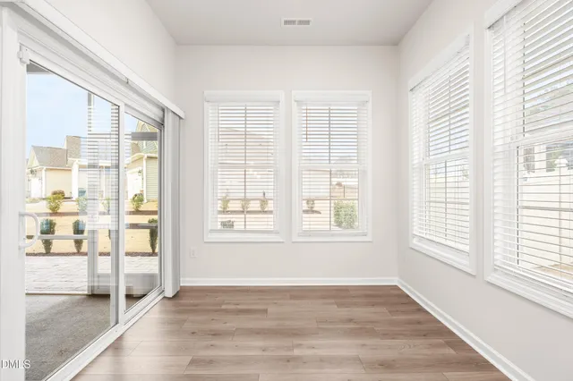 an empty room with wooden floor fan and windows
