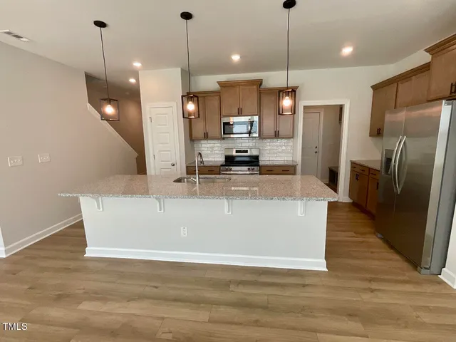 a view of a kitchen with stainless steel appliances granite countertop cabinets a refrigerator a sink and a wooden floor