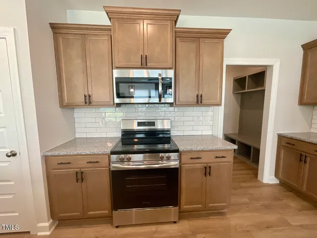 a kitchen with cabinets stainless steel appliances and wooden floor