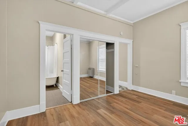 a view of a bedroom with wooden floor and bathroom