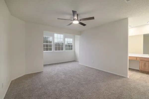 an empty room with windows and ceiling fan