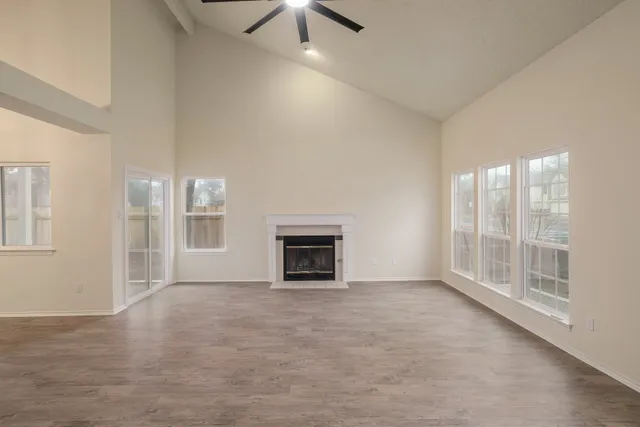 an empty room with windows and fireplace