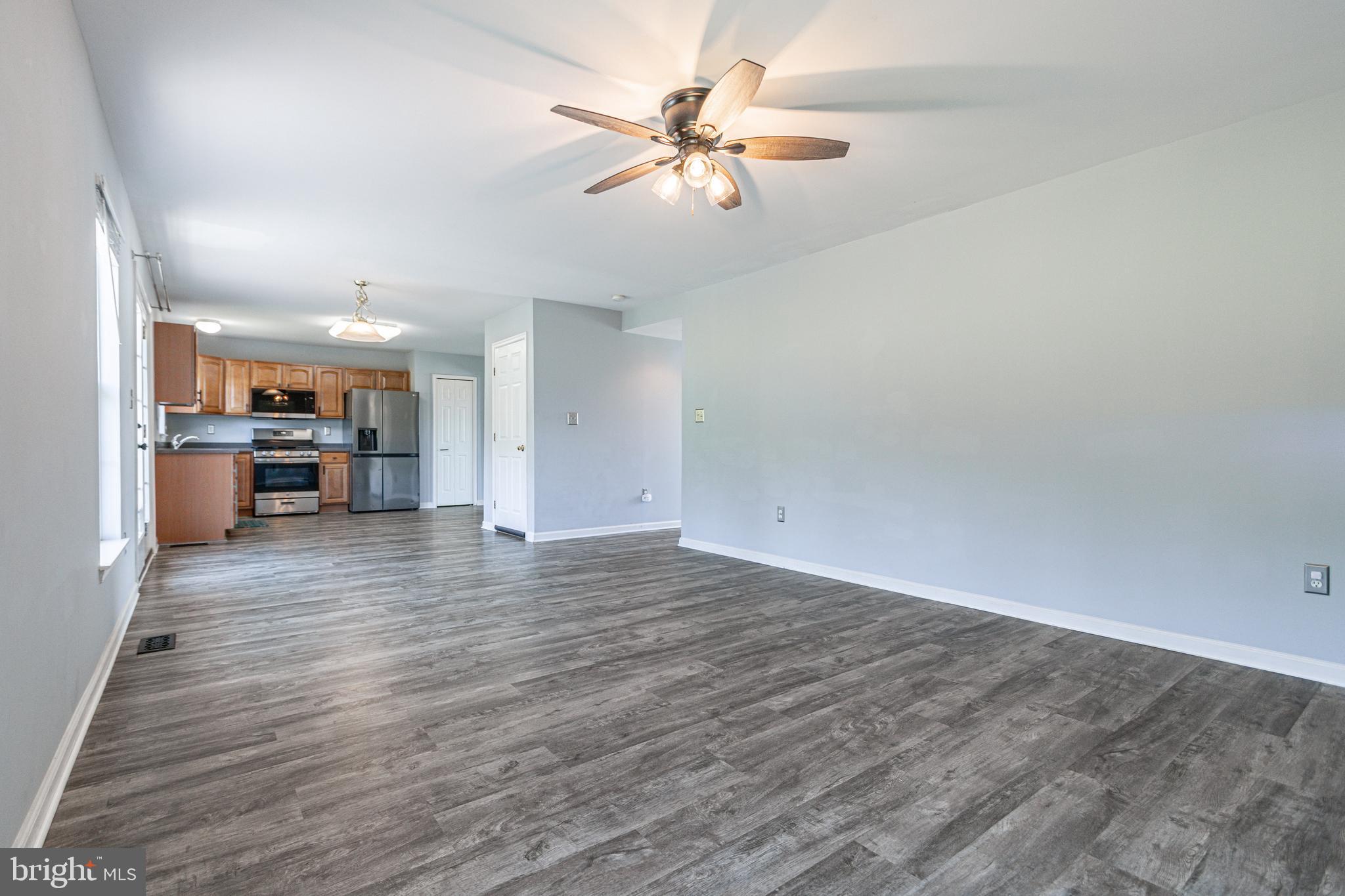 271 Courtney Court Spring Grove, PA 17362 - Photo 23 of 51 an empty room with wooden floor a ceiling fan and kitchen view