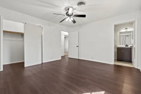 a view of an empty room with wooden floor and a ceiling fan