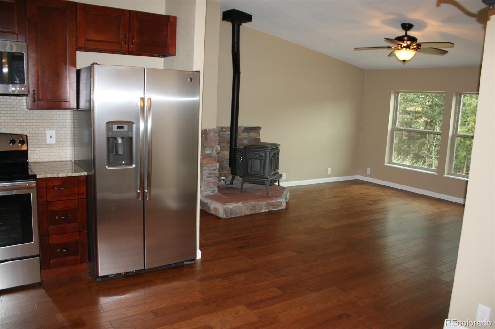 1078 Clark Road Bailey, CO 80421 - Photo 3 of 34 a view of a livingroom with wooden floor a ceiling fan and windows