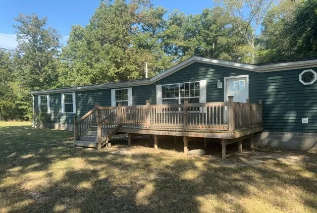 a backyard of a house with table and chairs potted plants and large tree