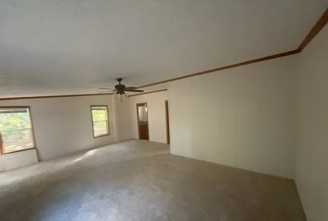 an empty room with windows and ceiling fan