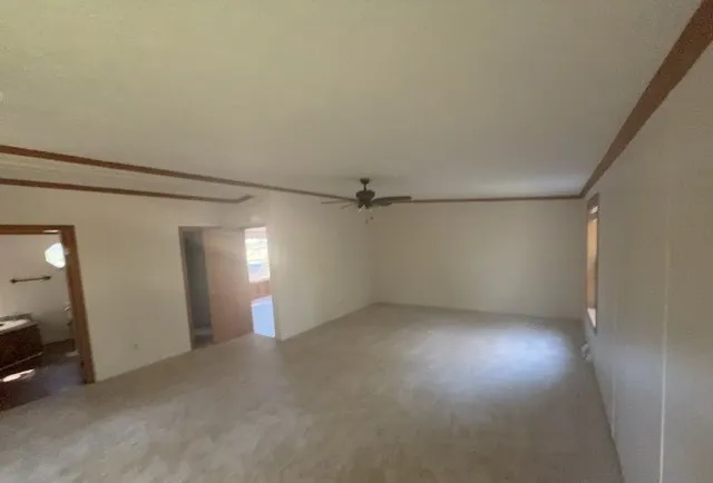 an empty room with a ceiling fan and window