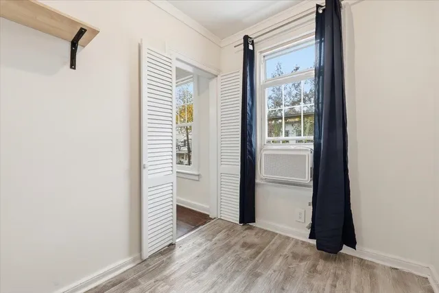 a view of a hallway with wooden floor and a bathroom