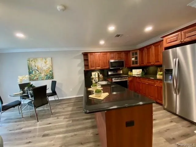 a kitchen with stainless steel appliances granite countertop a refrigerator a sink a stove a dining table and chairs