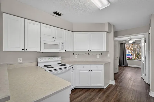 a kitchen with granite countertop white cabinets and white appliances
