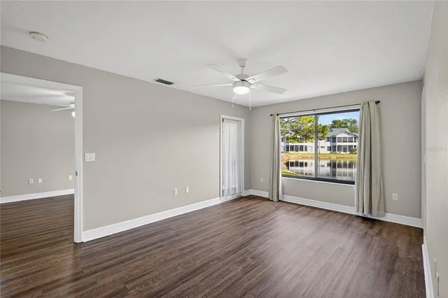 a view of an empty room with wooden floor and a window