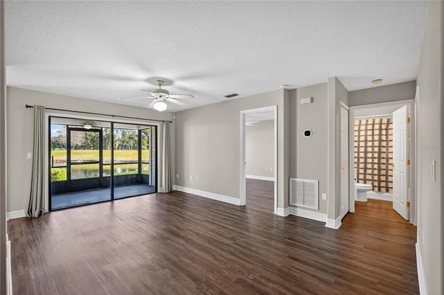 a view of empty room with wooden floor and fan