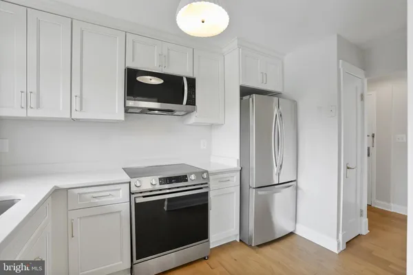 a kitchen with stainless steel appliances white cabinets and a refrigerator