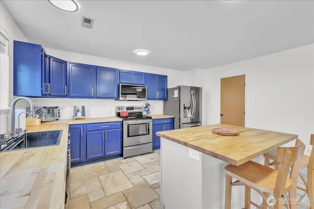 a kitchen with stainless steel appliances granite countertop a stove refrigerator a sink dishwasher and wooden cabinets with wooden floor