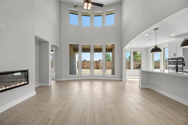 a view of an empty room with wooden floor and a kitchen