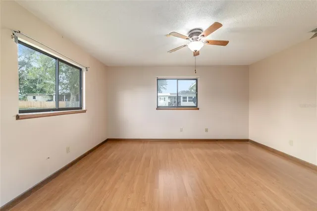 a view of empty room with wooden floor and fan