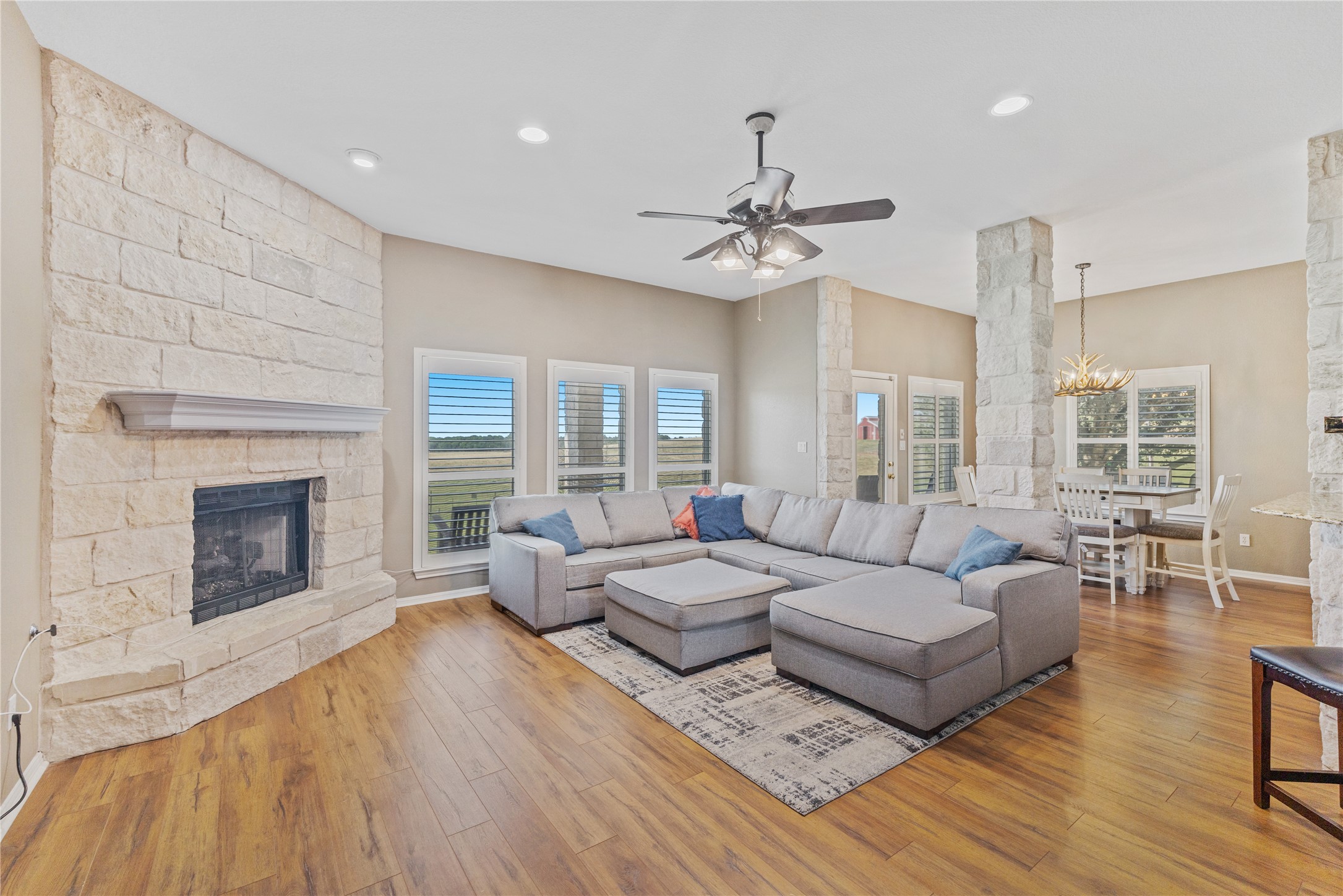 20145 Janak Road Coupland, TX 78615 - Photo 8 of 40 A spacious living area featuring a striking stone fireplace and rich hardwood flooring.