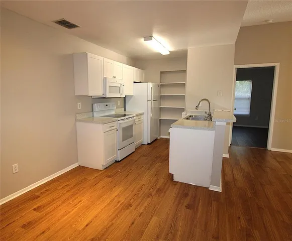 a kitchen with a sink cabinets stainless steel appliances and wooden floor