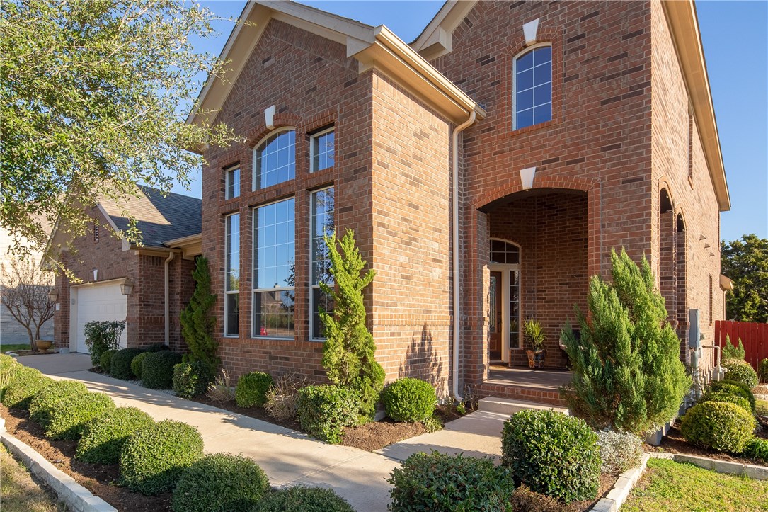 a view of brick house with a yard and plants