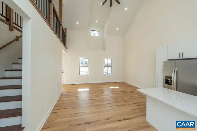 a view of an empty room with wooden floor and a hallway
