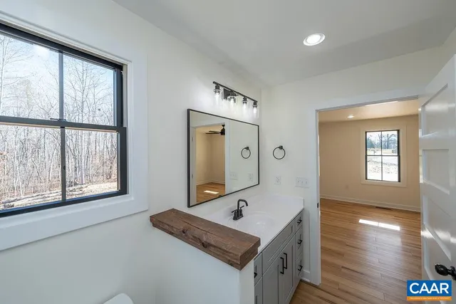 a bathroom with a sink a mirror and wooden floor
