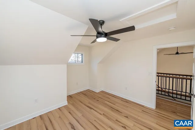 a view of a hallway with wooden floor and a ceiling fan