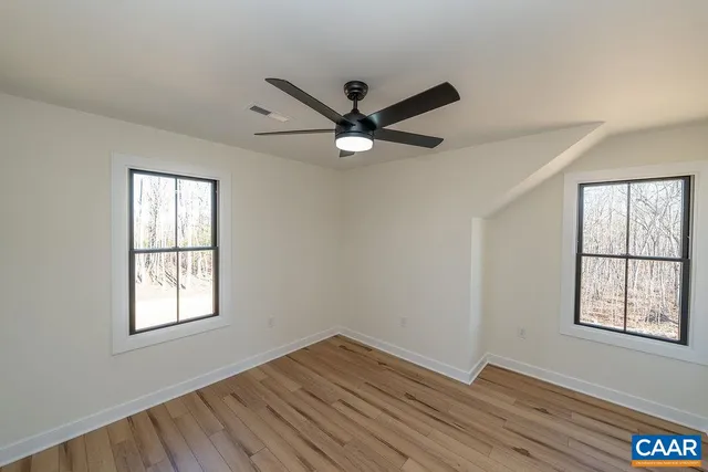 a view of an empty room with a window and wooden floor