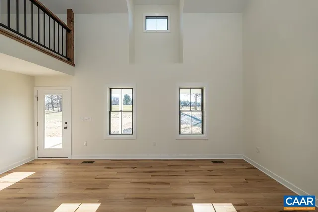 a view of an empty room with window and wooden floor