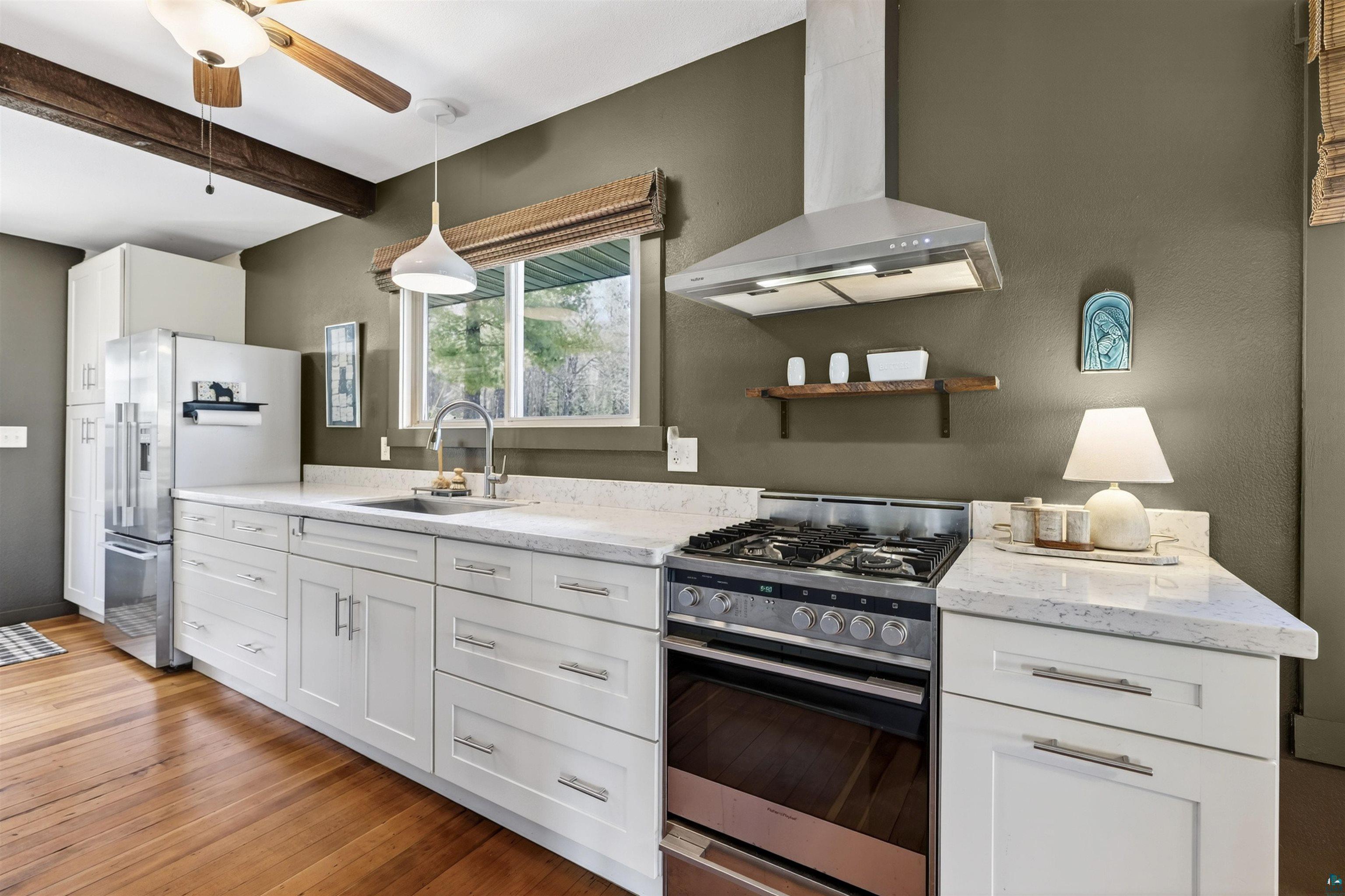 13885 Park Road Brule, WI 54820 - Photo 5 of 41 Kitchen featuring white shaker cabinetry, stainless steel appliances, wood-finish flooring, light-toned countertops, and a window with a woven shade