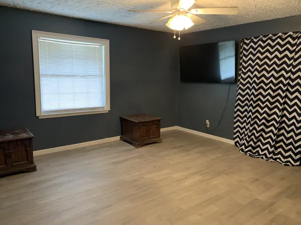 a view of an empty room with window and wooden floor