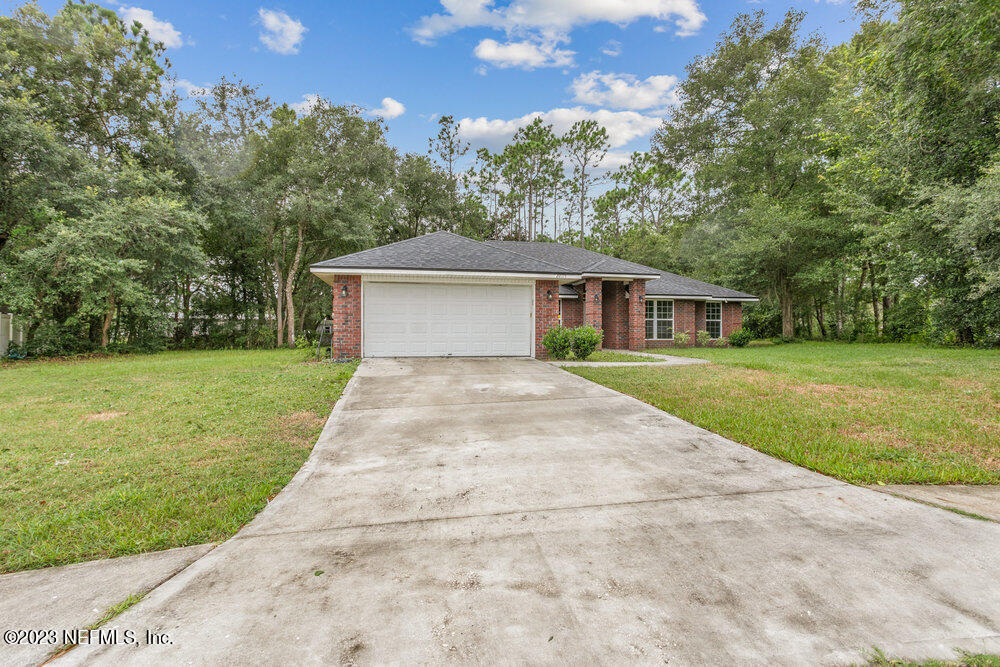 88175 Maybourne Road Yulee, FL 32097 - Photo 3 of 42 a white house with a small yard and large trees
