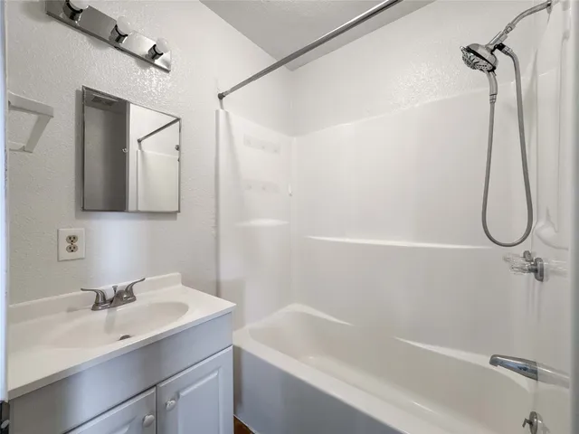 a bathroom with a tub sink vanity and mirror