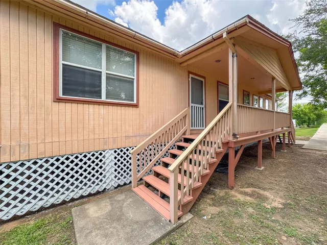 a backyard of a house with wooden deck stairs and furniture