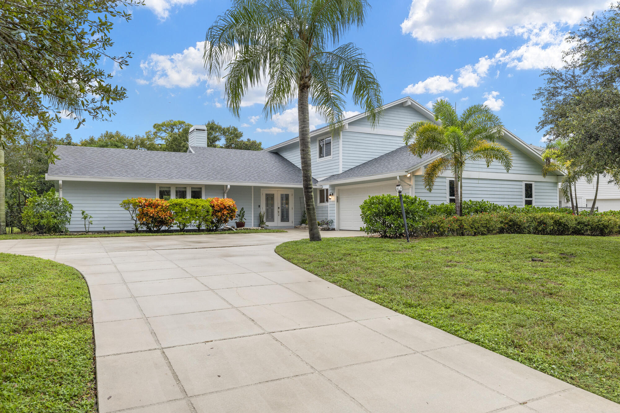 6595 Wood Lake Road Jupiter, FL 33458 - Photo 1 of 54 a front view of a house with a yard and garage